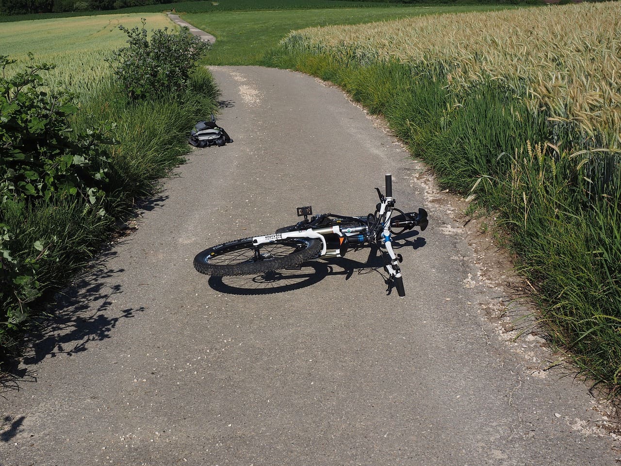 A bicycle laying on the ground in front of some grass