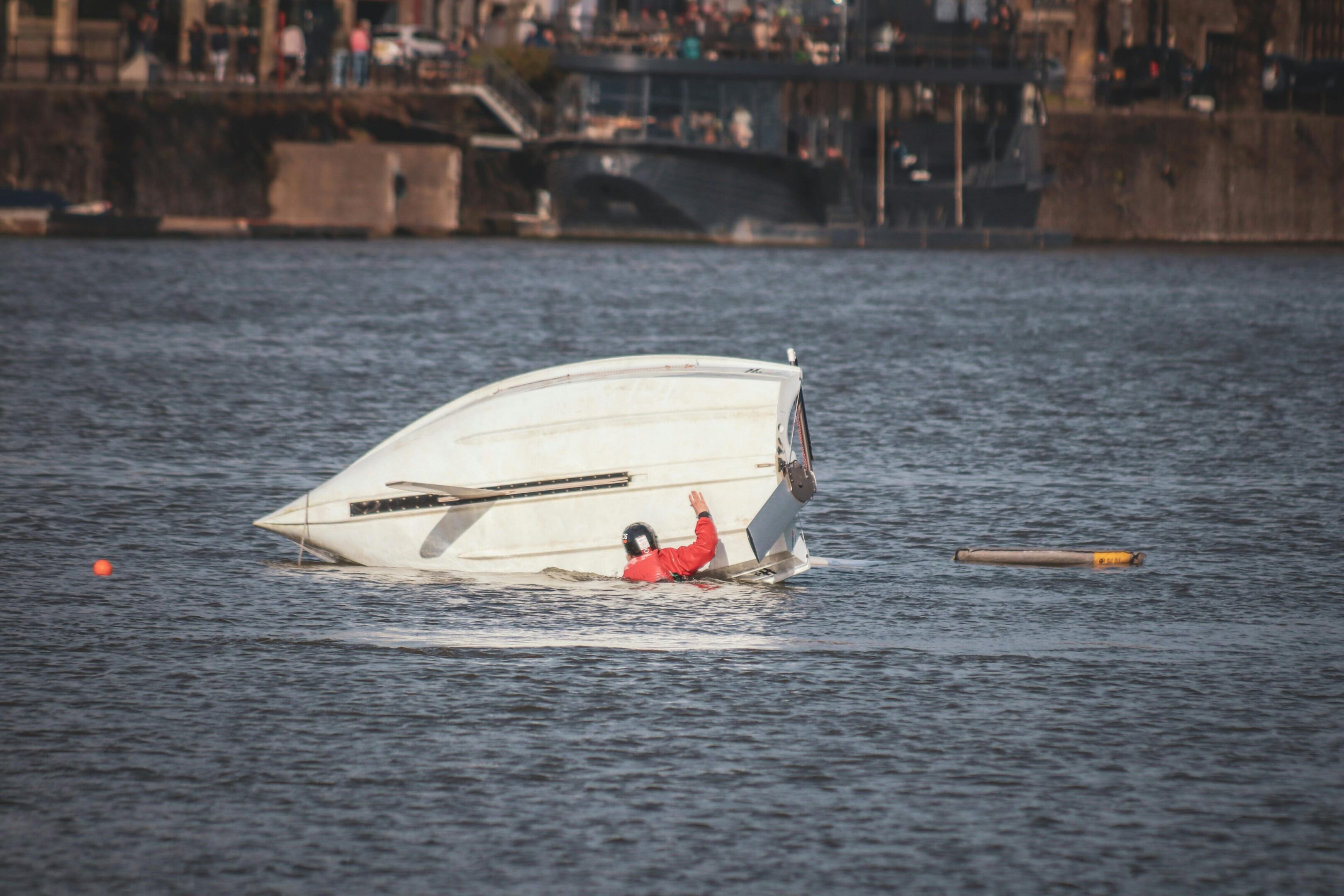 A person is sitting on the back of a boat in water.