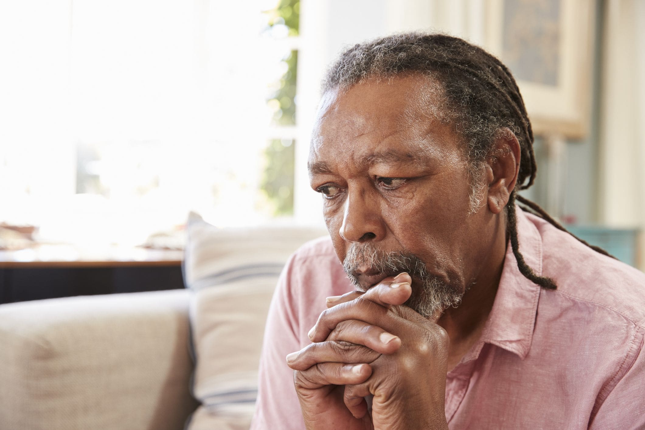20PcYiEA A man with dreadlocks is sitting down and holding his hands together.